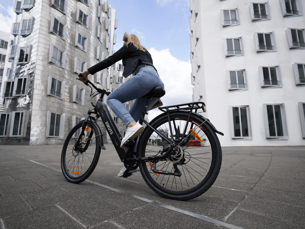 En kvinna cyklar elcykel utan hjälm i staden