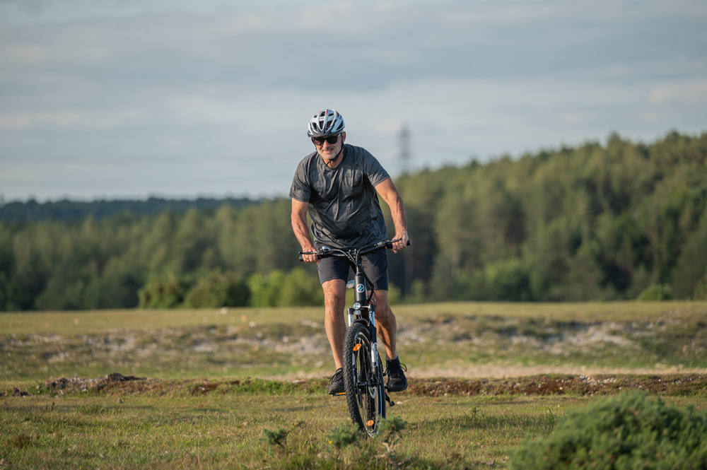 En man med hjälm cyklar i vildmarken med en Netuno elcykel