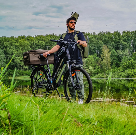 En man med en väska som cyklar på en elcykel i naturen