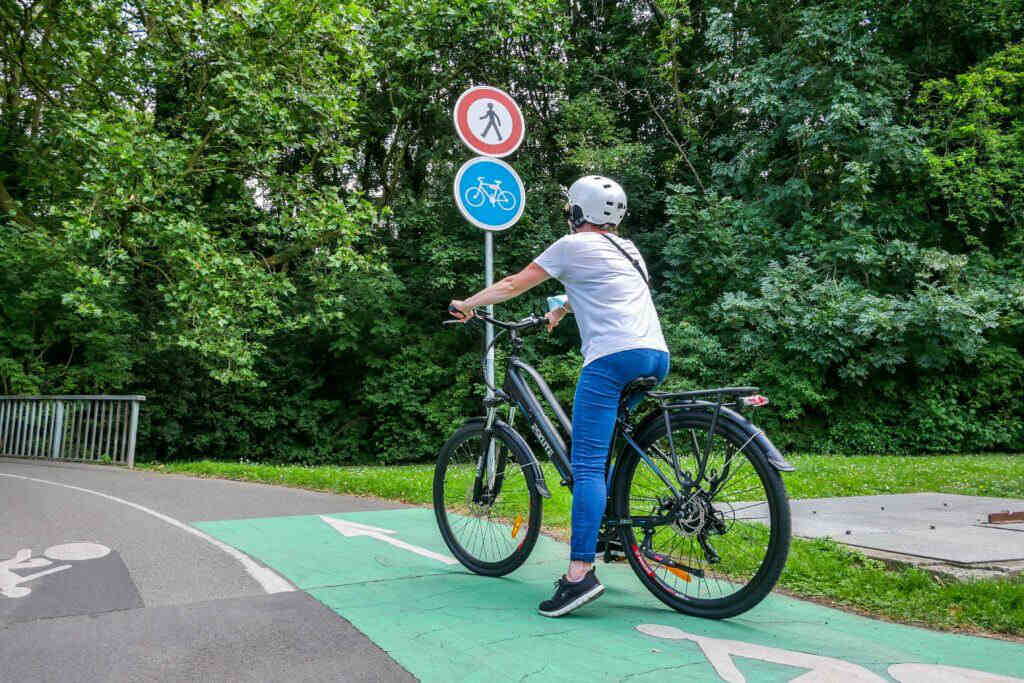 En kvinna med hjälm cyklar på en elcykel på cykelvägen