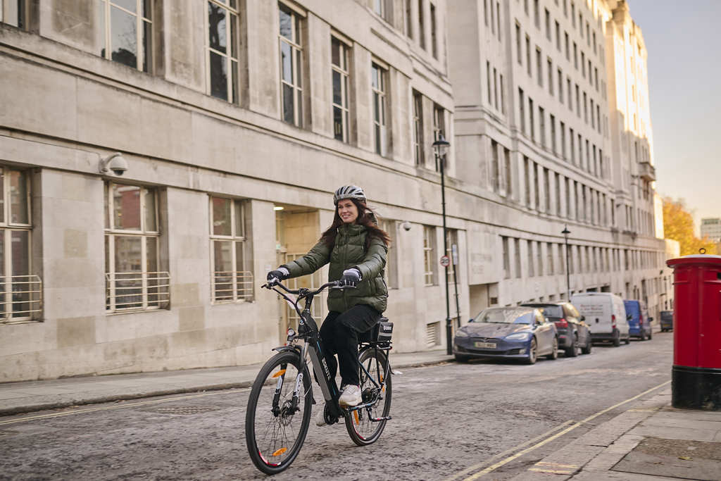 En kvinna cyklar på en elcykel med trampstöd