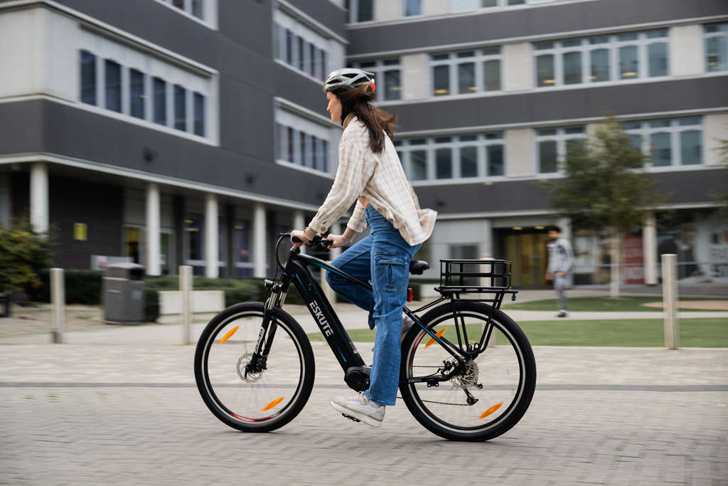 En ung dam cyklar elcykel med pakethållarkorg
