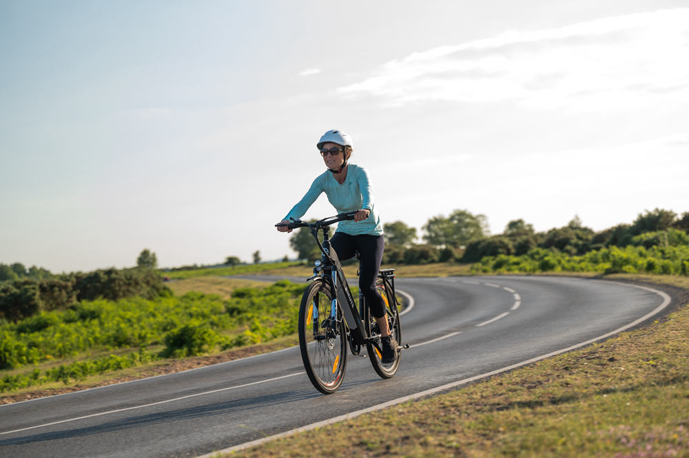 Kvinna med hjälm cyklar på en Polluno elcykel på vägen