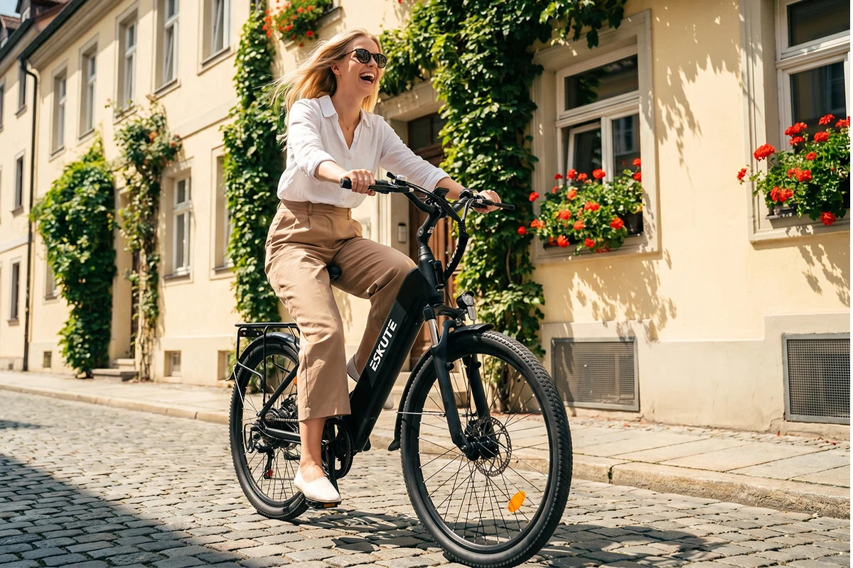 Frau fährt ein schwarzes C202 City-E-Bike auf Kopfsteinpflasterstraßen mit begrünten historischen Gebäuden