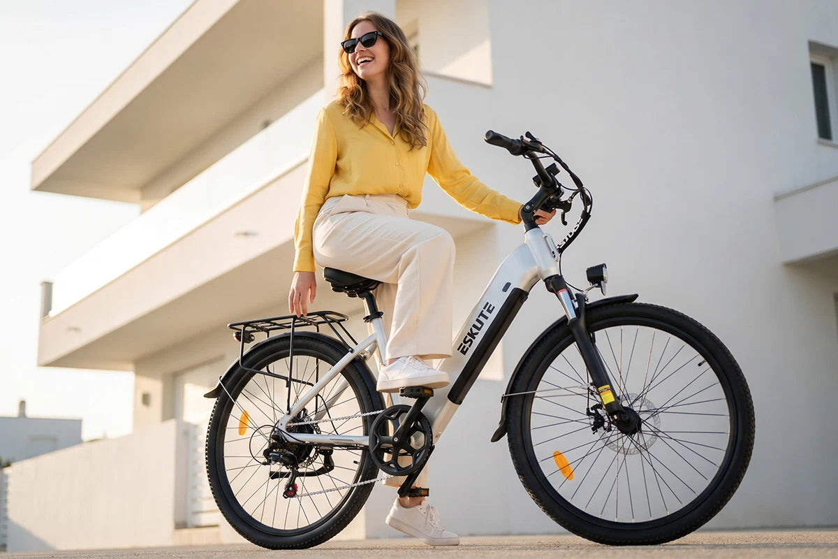 Frau auf dem weißen C202 City-E-Bike vor moderner weißer Architektur, lächelnd und elegant unterwegs