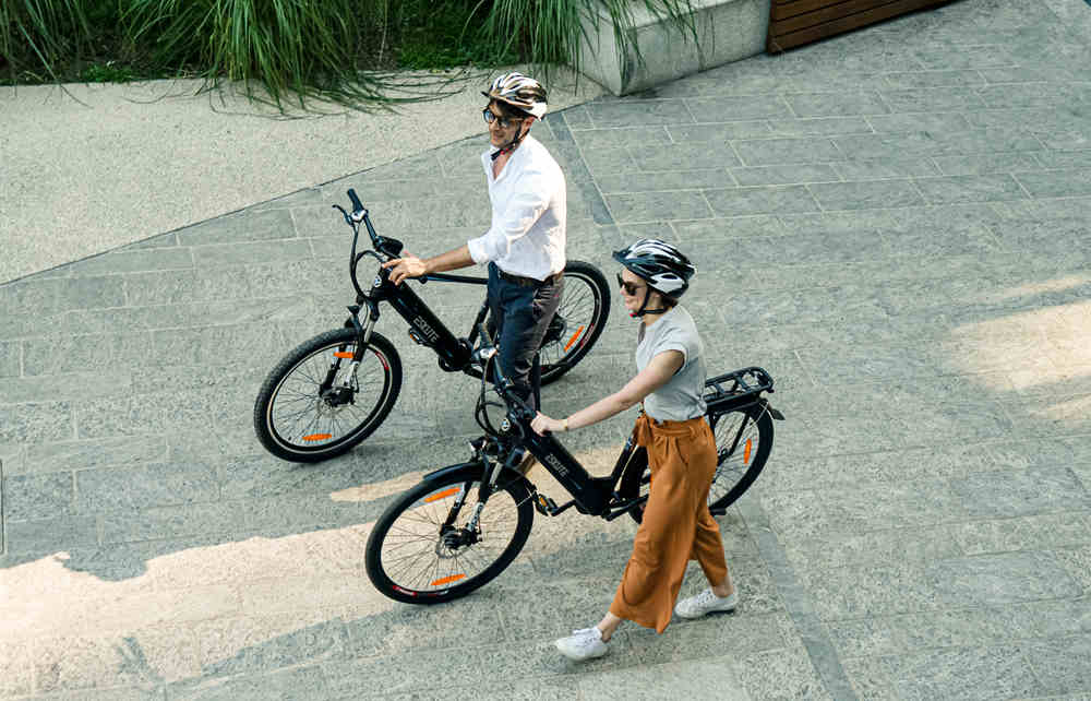 en man och en kvinna skjuter sina elcyklar framåt