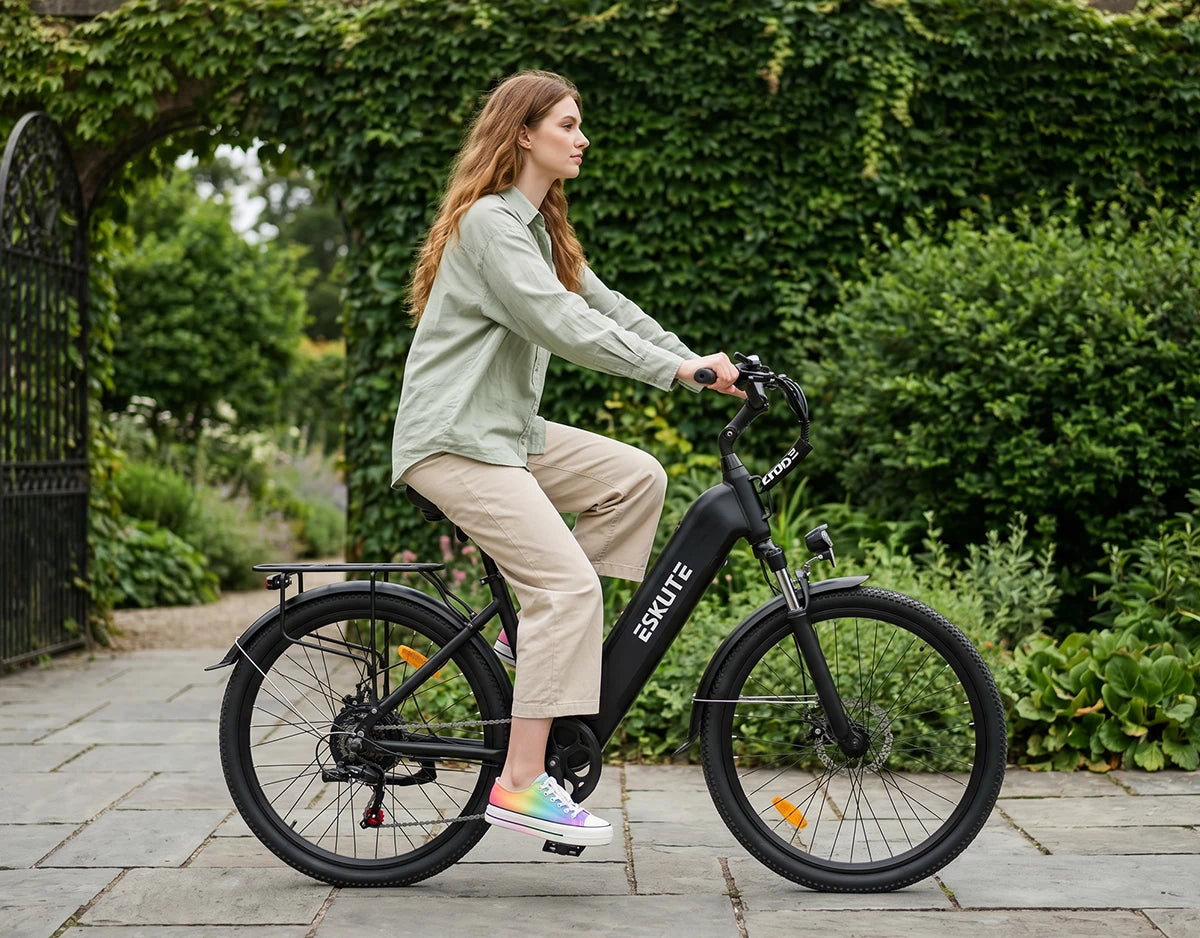 Frau fährt mit dem schwarzen Eskute C202 City-E-Bike ruhig entlang eines grünen Gartens.