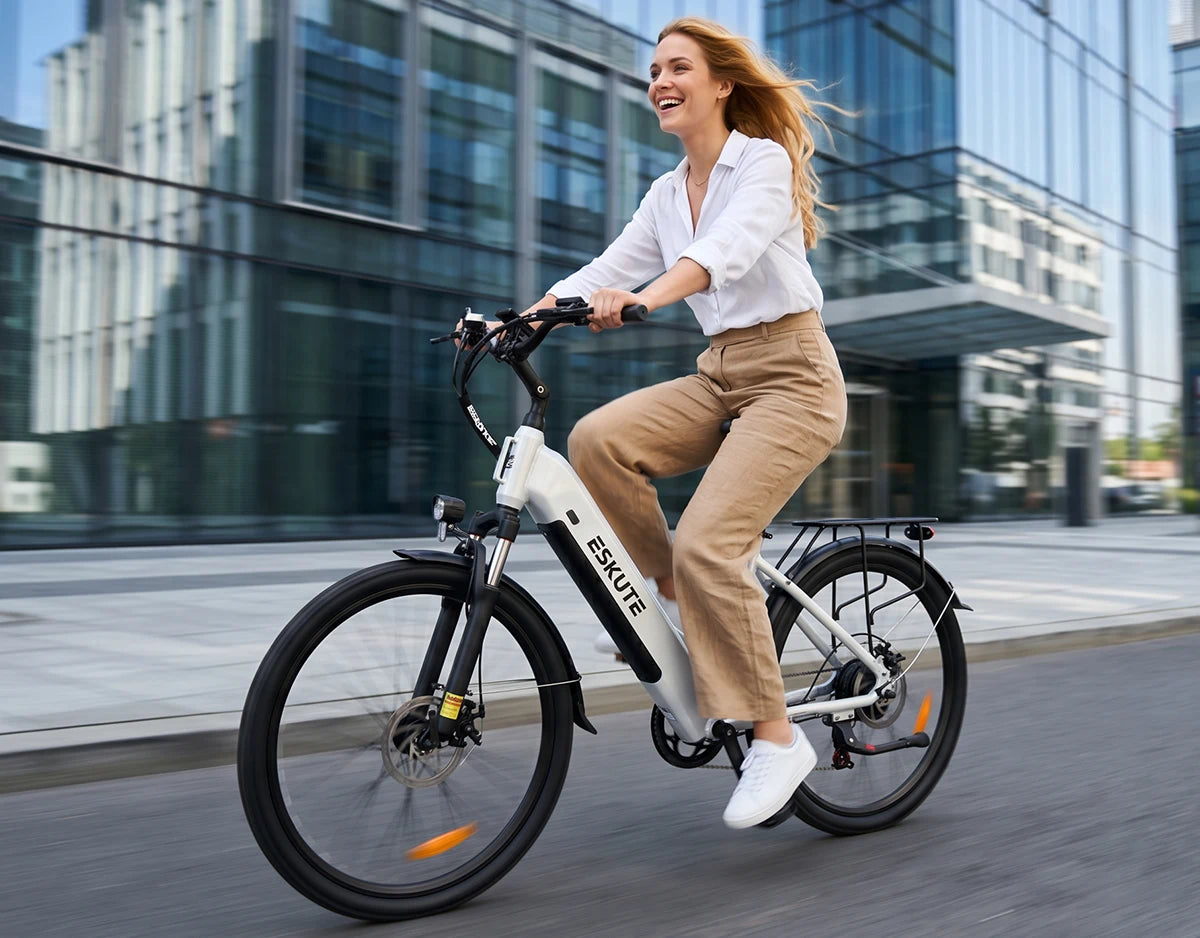 Frau fährt mit dem weißen Eskute C202 City-E-Bike vor modernen Wolkenkratzern zur Arbeit.