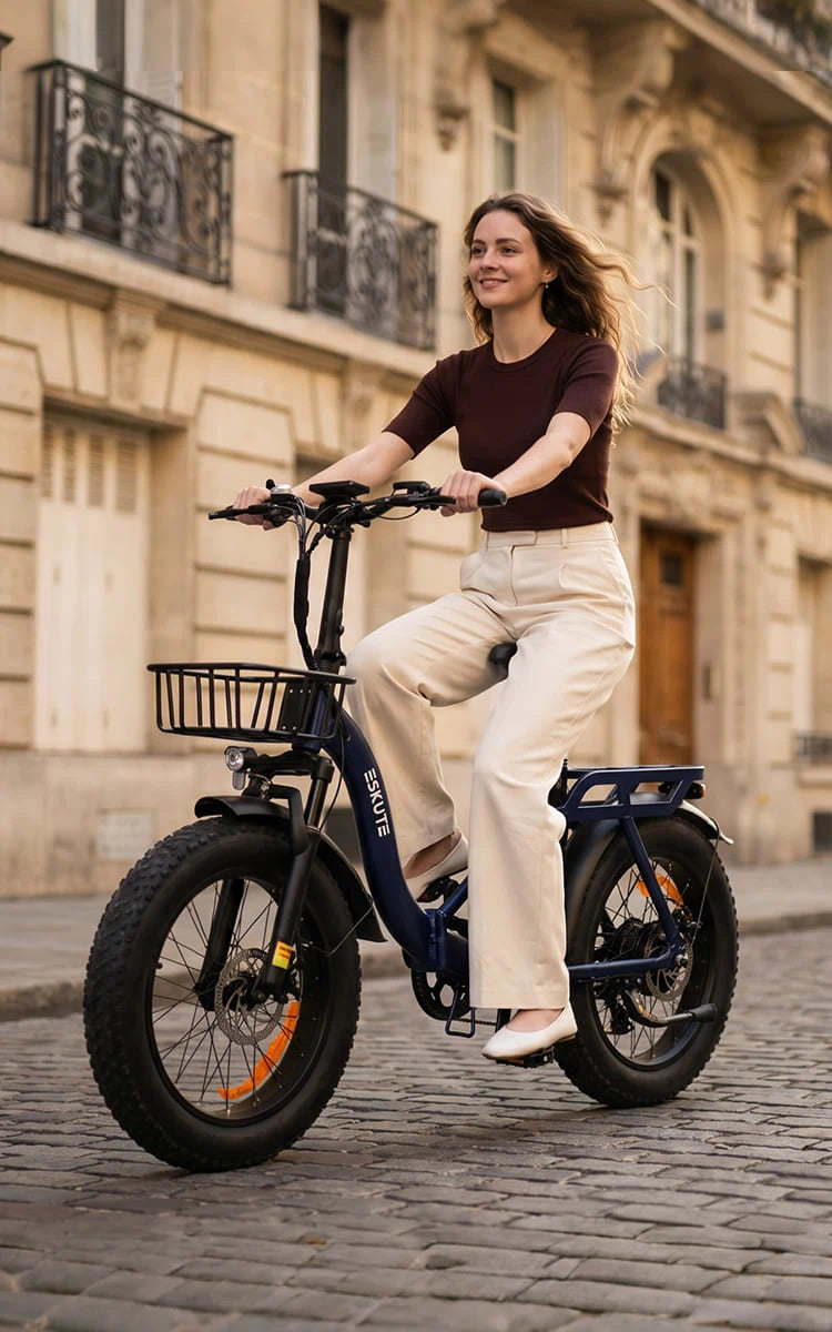 Frau fährt ein klappbares Fat-Tire E-Bike von Eskute durch eine europäische Stadt auf Kopfsteinpflaster
