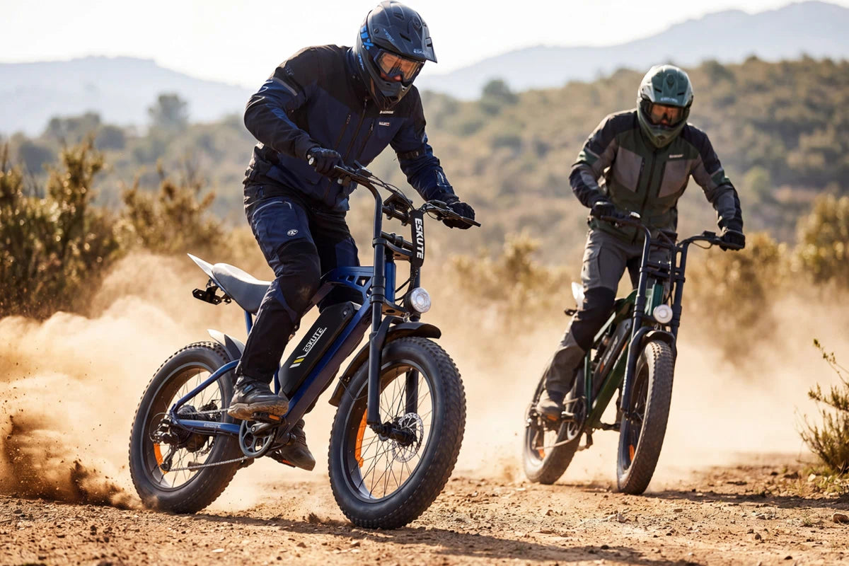 Two riders in protective gear drifting on V202 retro fat tire electric bikes on a dusty off-road mountain trail.