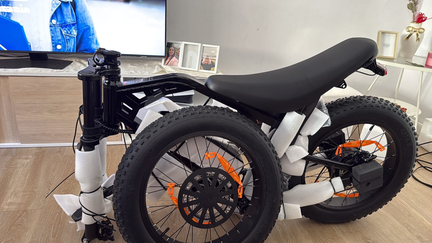 Customer's black Eskute V202 Retro E-Bike partially unpacked, showing tires with protective foam wrapping indoors.