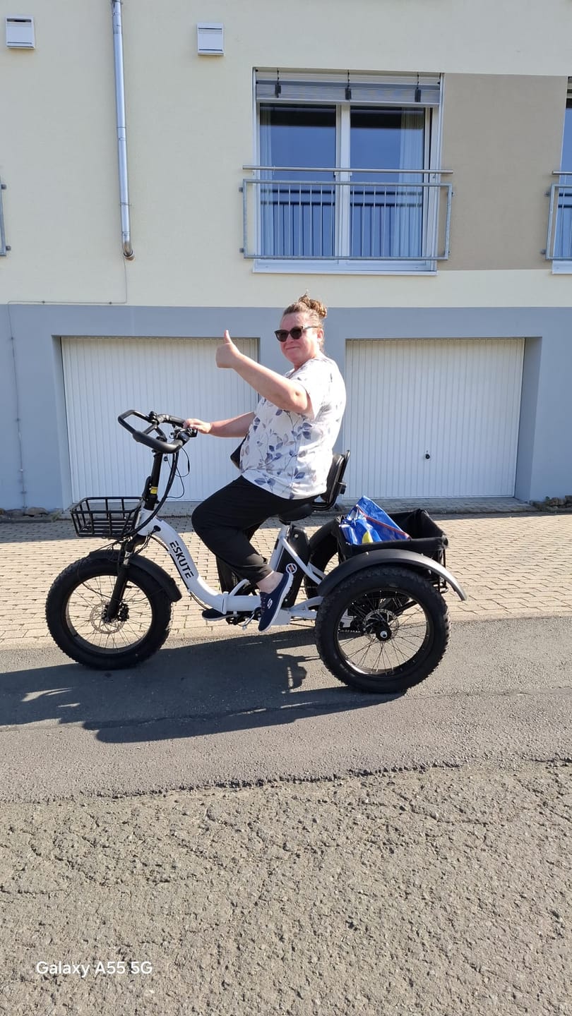 Customer's white Eskute T302 Pro Cargo E-Bike with a rear basket, being ridden outdoors by a person giving a thumbs up.