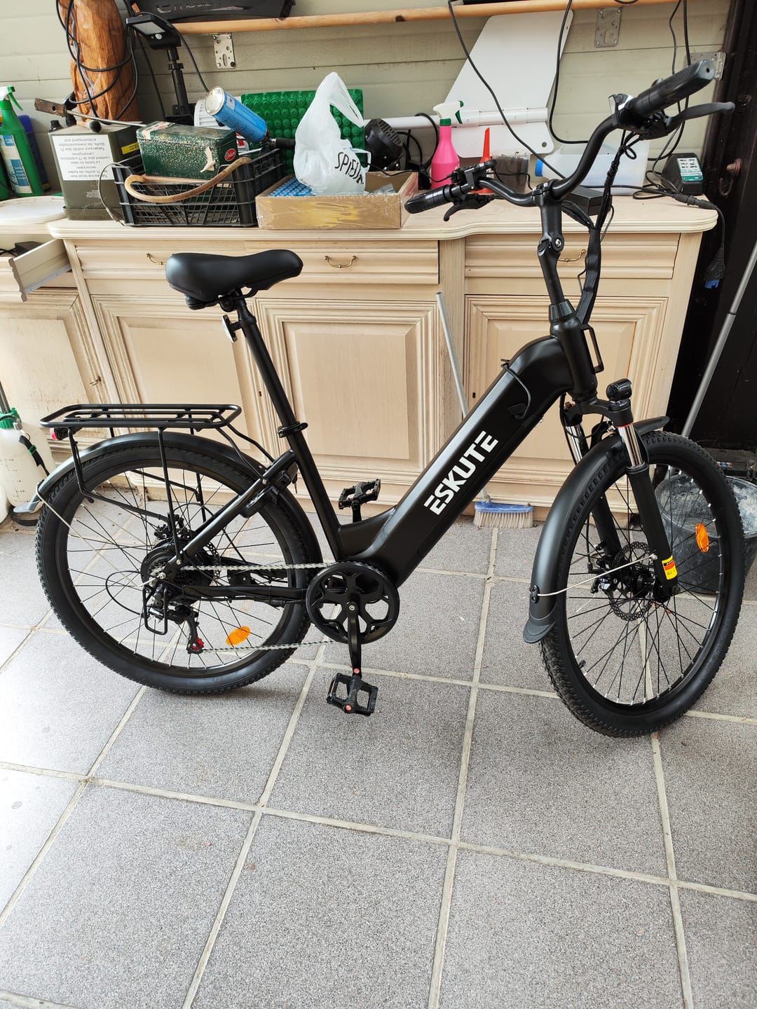 Customer's black Eskute C202 City E-Bike parked in an indoor space with a tiled floor.