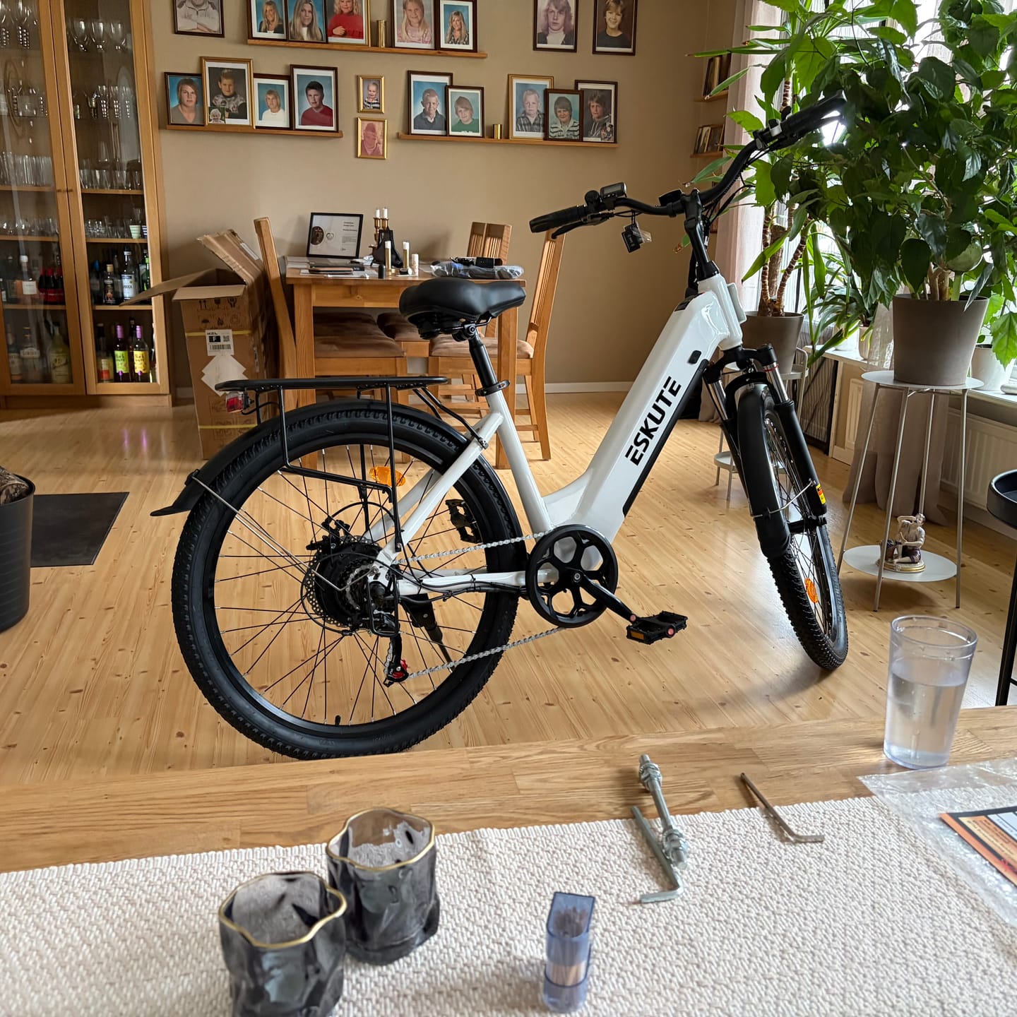 Customer's white Eskute electric bike standing in a living room, partially assembled with tools on a table.